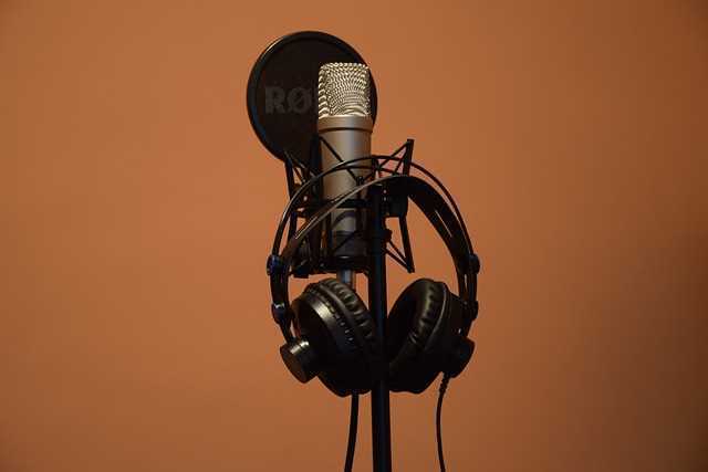 A photo of a microphone and headphones set against an orange background